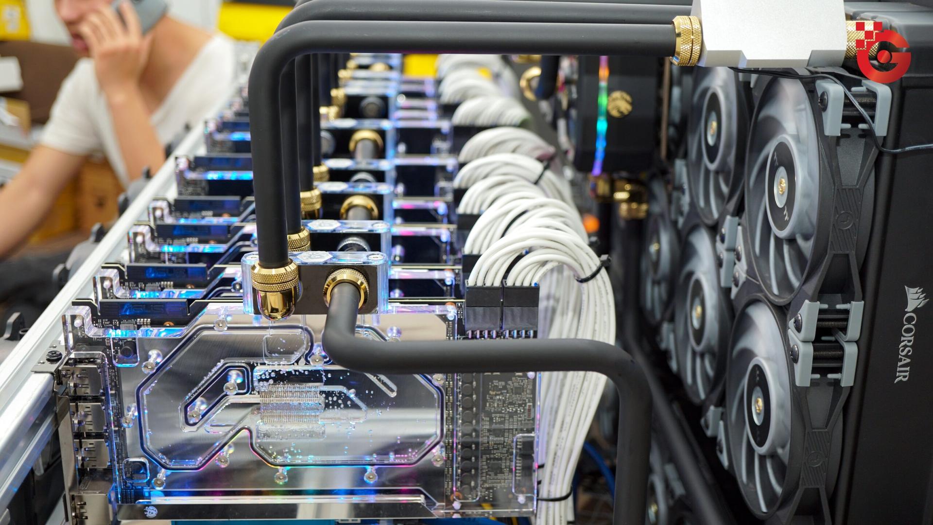 Row of water-cooled ASUS graphics cards in a mining rig, joined by black coolant tubes and white power cables